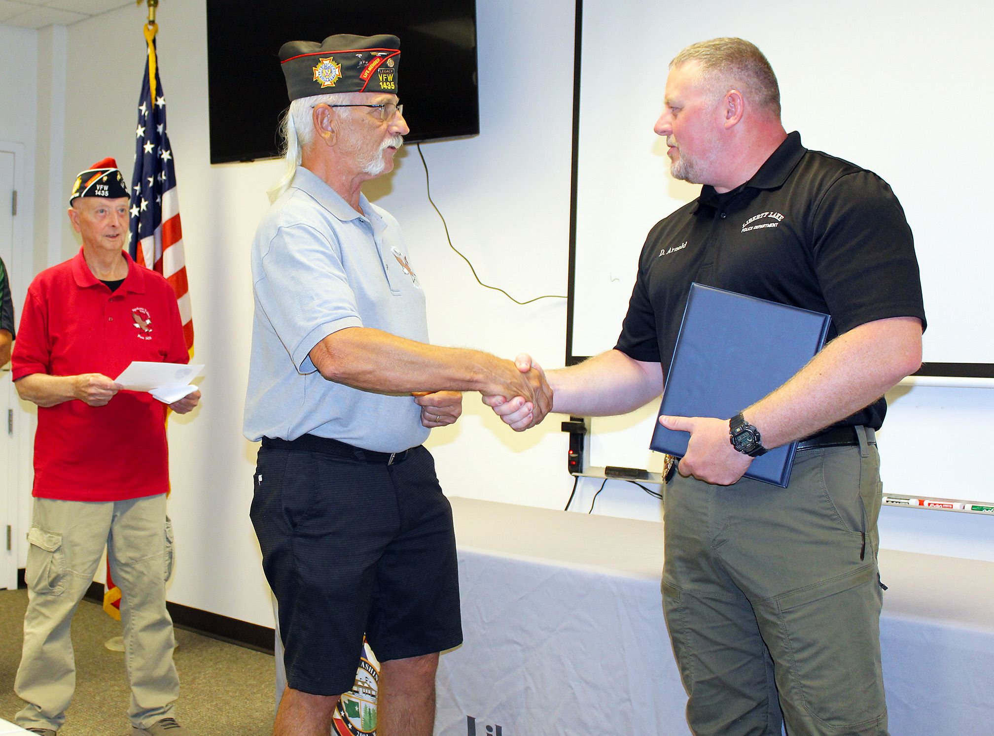 Derek Arnold receiving VFW Award coin from Darren Hughes